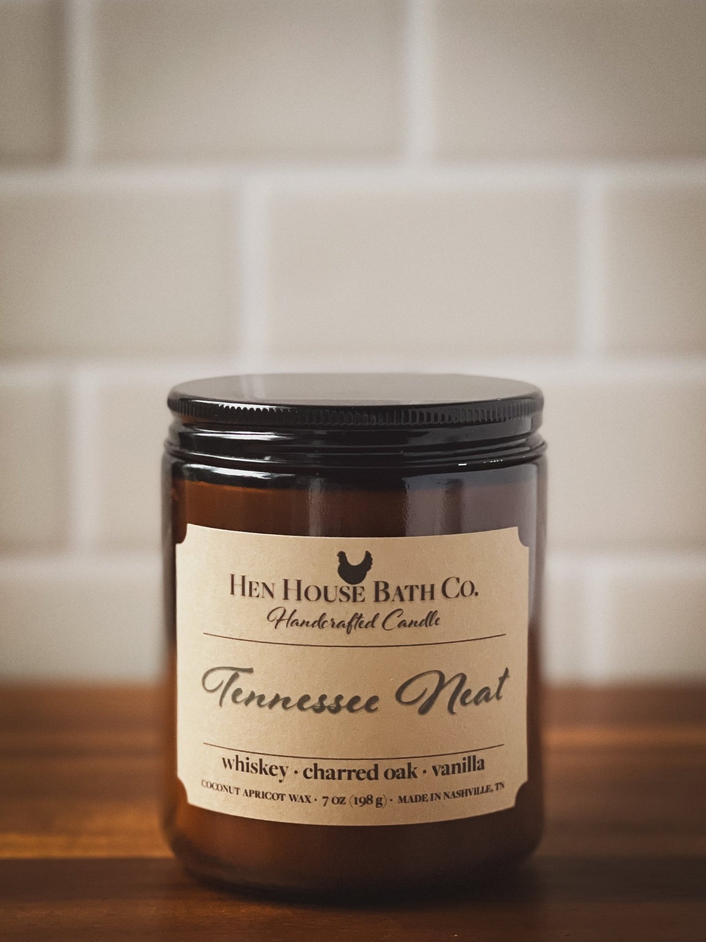 Tennessee Whiskey coconut-apricot wax candle by Hen House Bath Co. on rustic wood with moody southern styling
