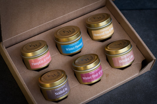 Element House Fall/Winter Discovery Box open to reveal six labeled 2 oz gold mini candles, including Pumpkin & Flannel, Winter Passage, Honeyed Tea & Pear, Sleeping Late, Winter Fruit & Spice, and Nestled In.